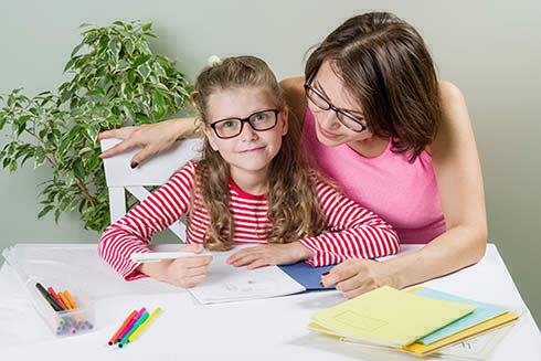 Femme aidant une petite fille à faire ses devoirs